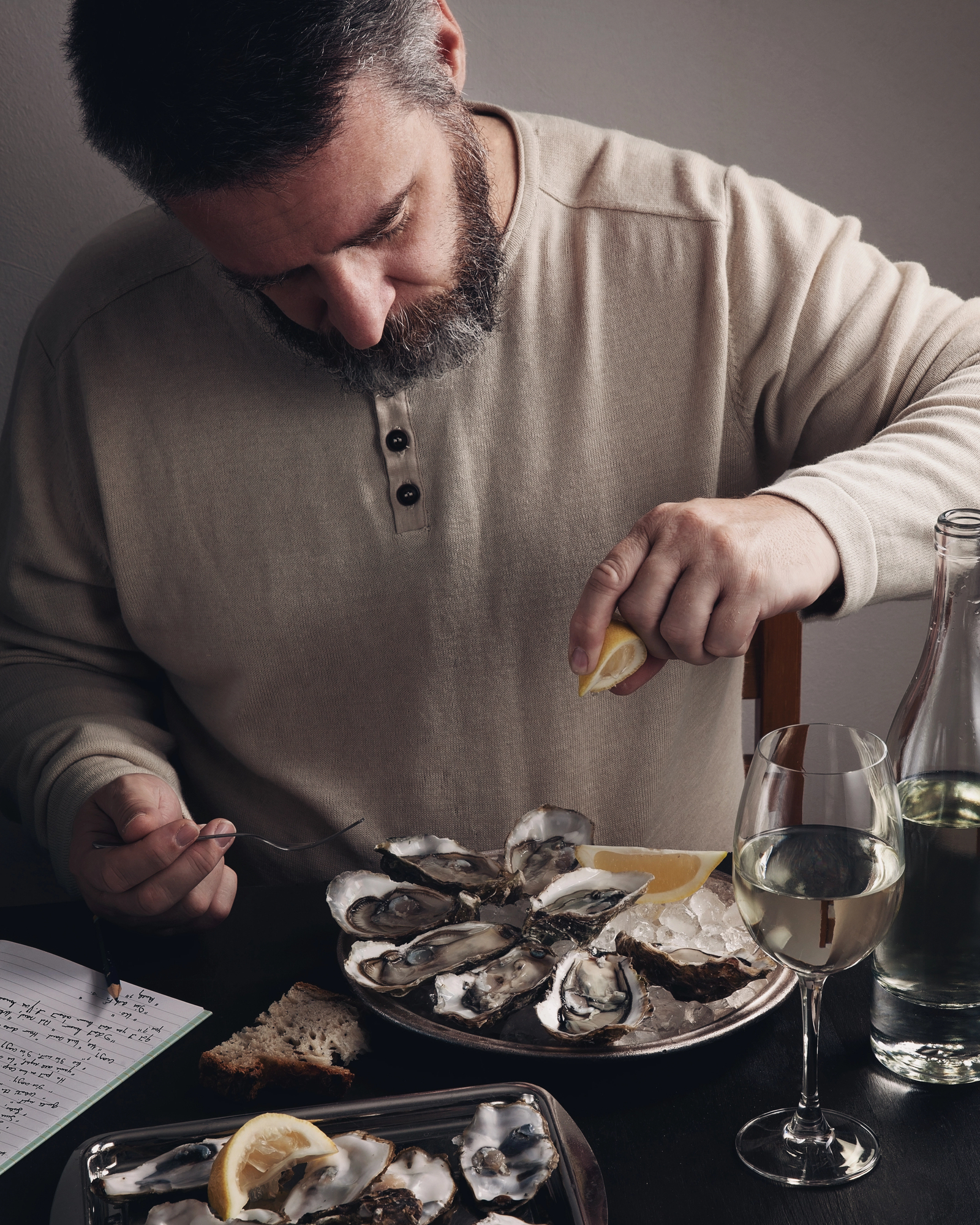 man eating six oysters, squeezing lemon juice over man eating oysters